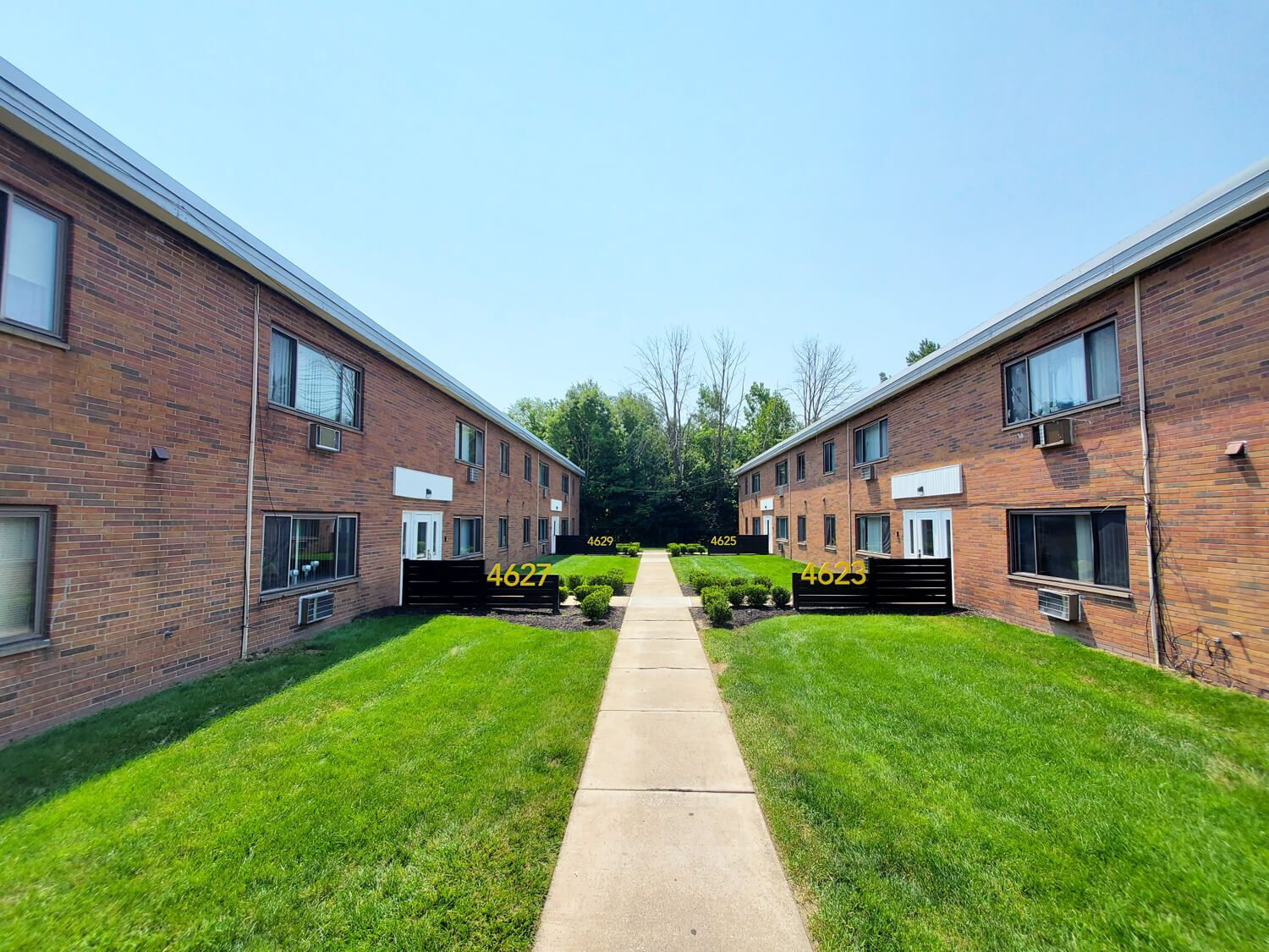 Brick apartment courtyard with lawn and walkway at One-3-One Apartments.