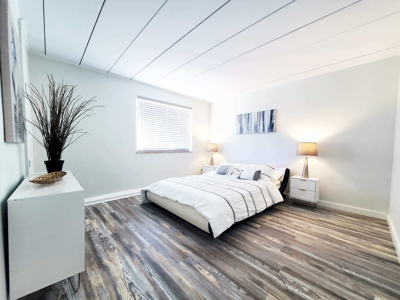 Renovated apartment bedroom with wide-plank flooring and fresh white walls.
