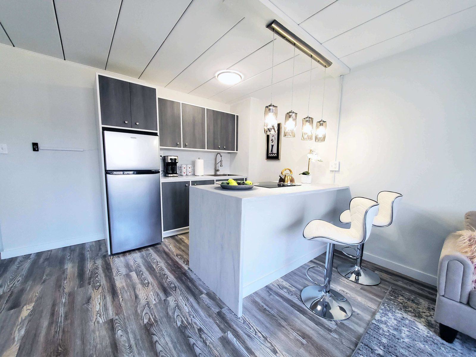 Renovated open apartment kitchen with a waterfall island, bar stools and pendant lighting.
