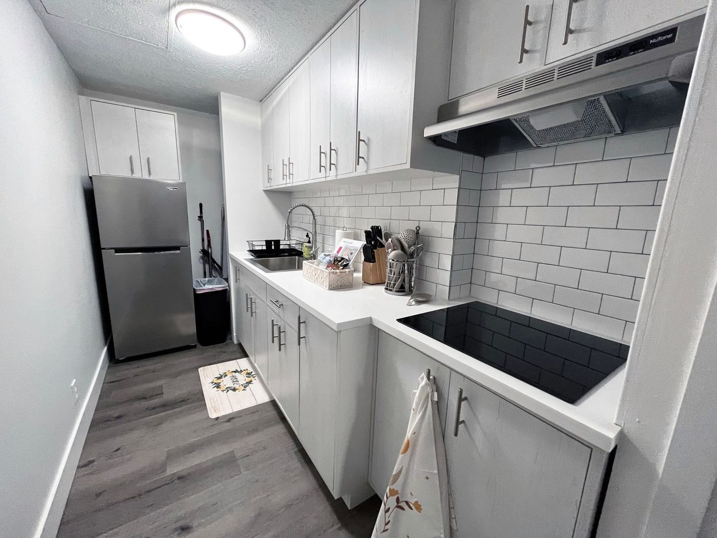 A renovated apartment kitchen with white cabinets, subway tile backsplash and stainless appliances.