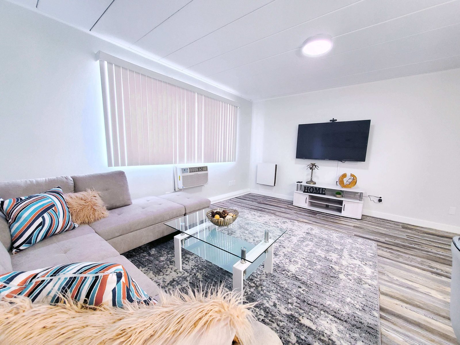 A completed apartment living room with new flooring, paint and lighting.
